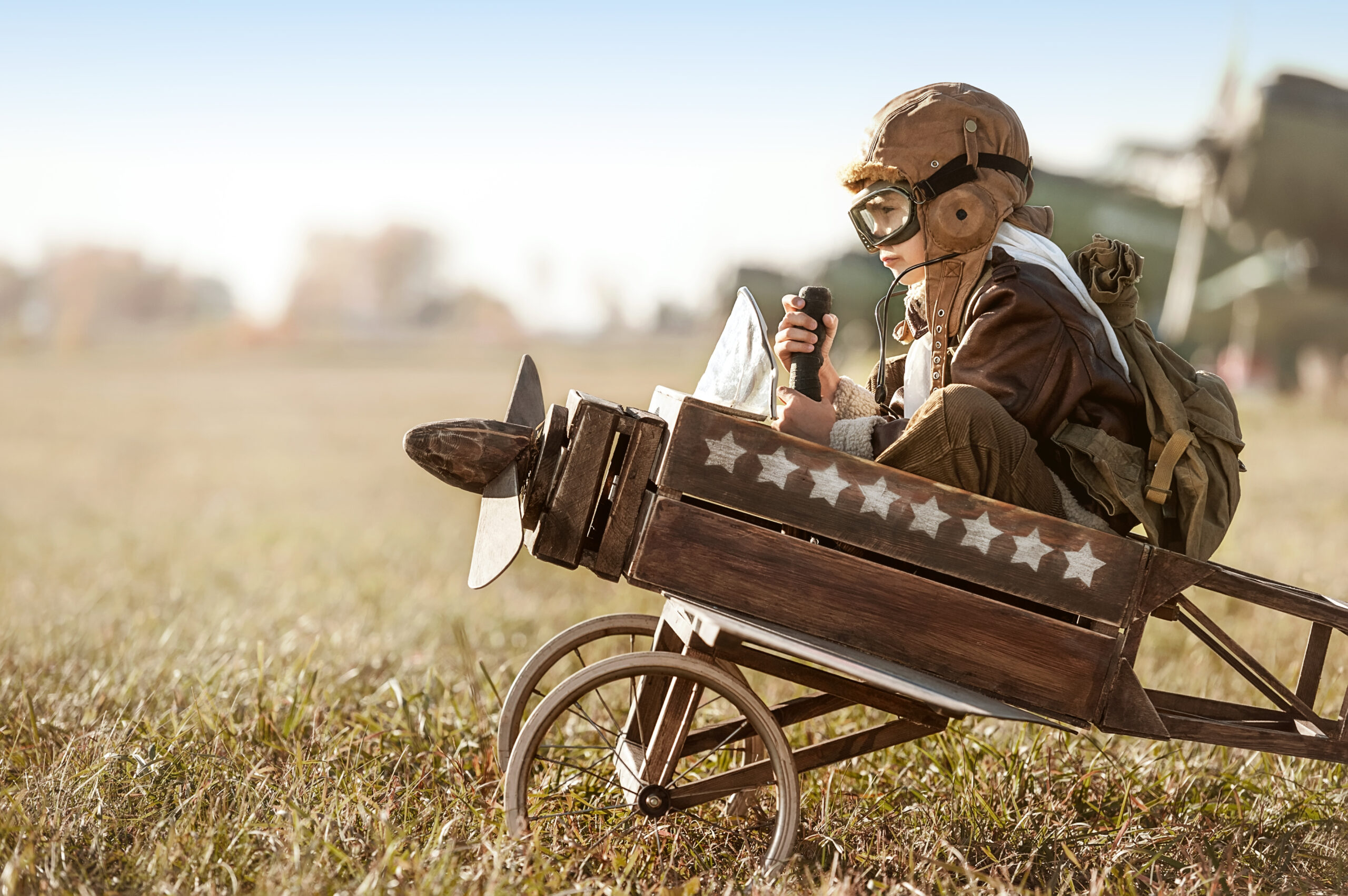 Young Aviator sits in his makeshift toy airplane on airport parking